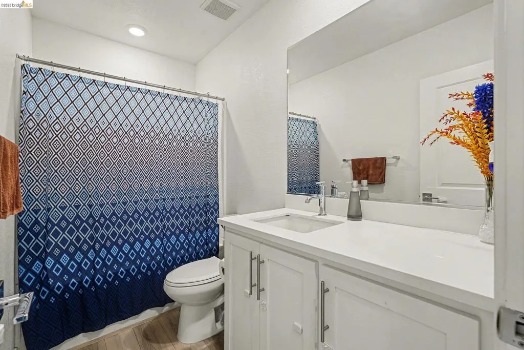 Bathroom featuring a white vanity with an integrated sink, polished chrome faucet, and a large mirror