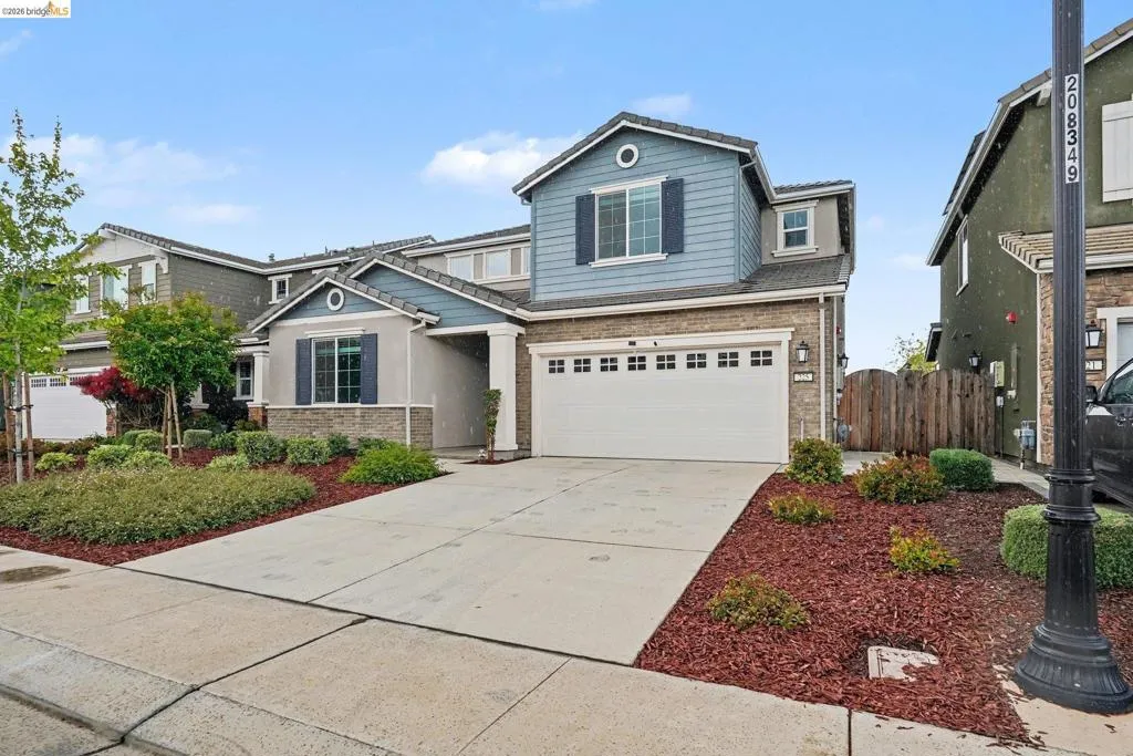 Contemporary two-story residence featuring a two-car garage, stone and siding exterior accents, and a covered porch entry