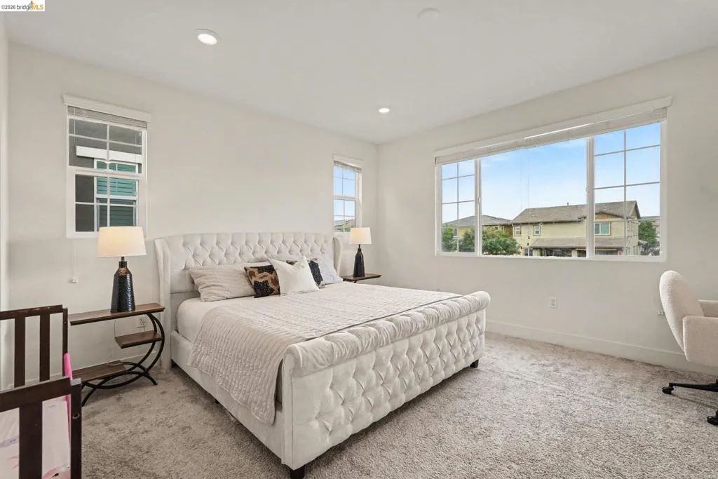 Carpeted room featuring multiple windows with roller blinds, recessed lighting, and white baseboards