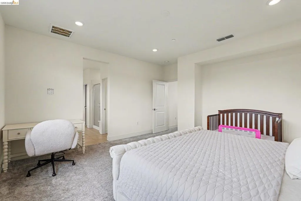 Spacious room featuring light-colored walls, recessed lighting, and gray carpeted flooring