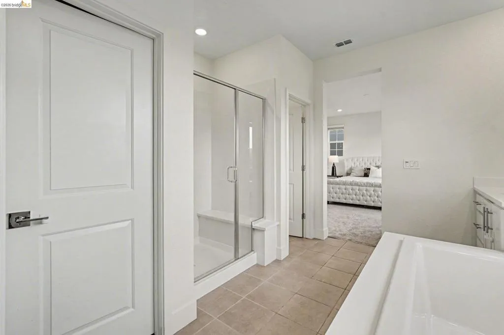 Bathroom with a glass-enclosed shower featuring a built-in bench, a separate soaking tub, and tile flooring