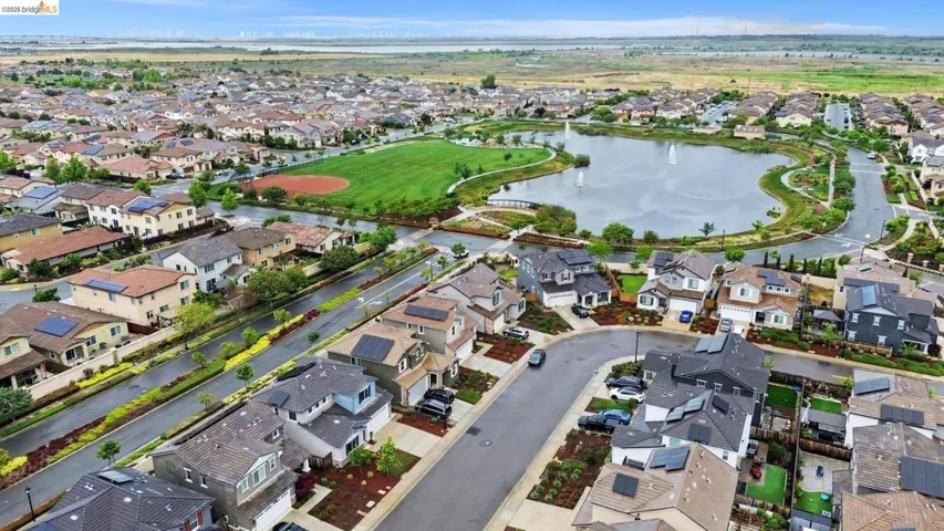 Expansive residential development featuring a central lake with fountains, green spaces, and a baseball field