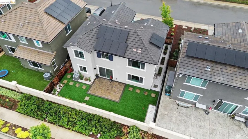 Rear exterior featuring a paver patio, artificial turf lawn, and a perimeter wall