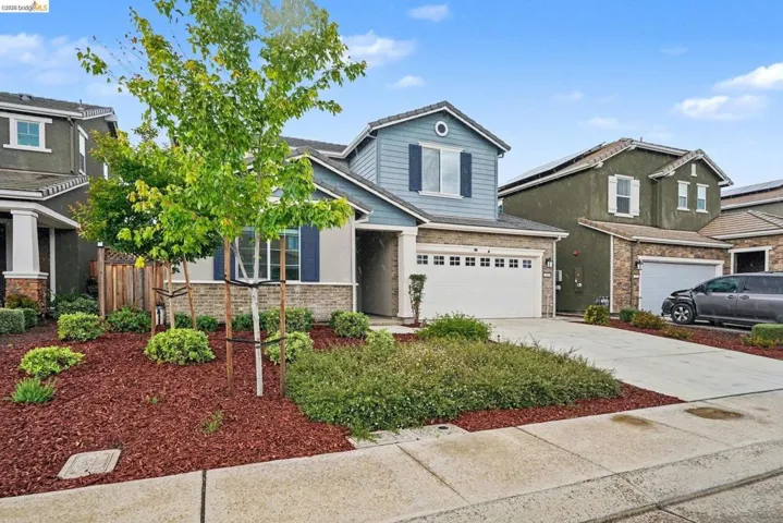 Contemporary two-story residence featuring a two-car garage, stone and siding exterior, and a manicured front yard with mature trees
