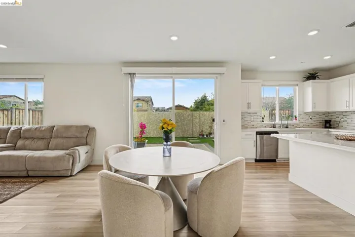Open-concept interior featuring light wood-finish flooring, recessed lighting, and a sliding glass door to the backyard
