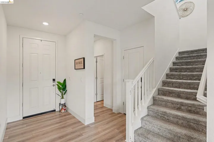 Entryway featuring a paneled door, wood-finish flooring, recessed lighting, and a carpeted staircase with white balusters