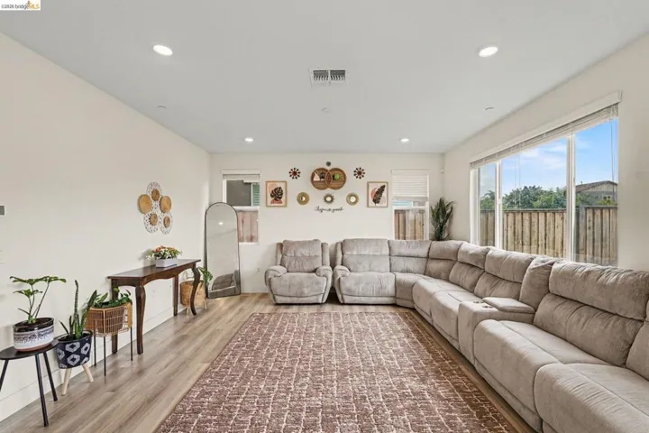 Spacious living area featuring expansive windows, wood-finish flooring, recessed lighting, and a neutral color palette