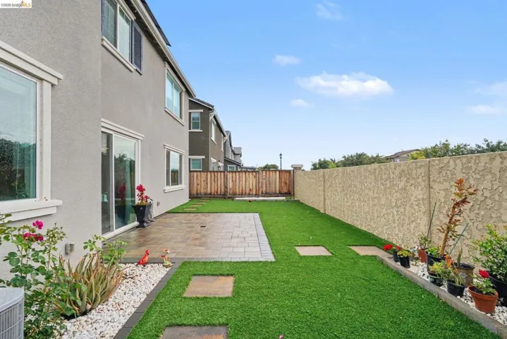 Expansive backyard featuring a paver patio, artificial turf lawn, and stepping stones