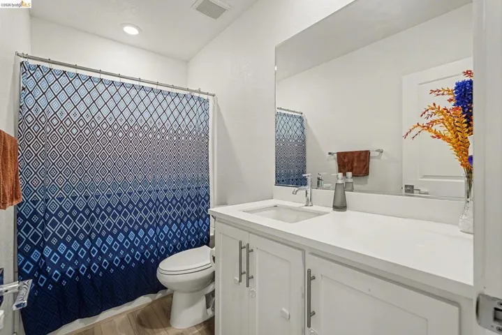 Bathroom featuring a white vanity with an integrated sink, polished chrome faucet, and a large mirror