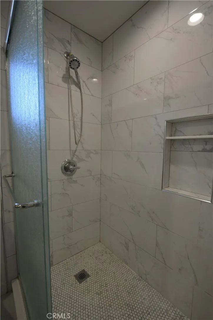Specious walk-in shower with tiled floors and walls