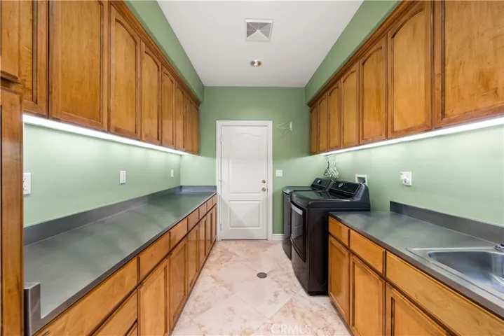 Laundry Room with Loads of Cabinets, Stainless Steel Countertops, Utility Sink and Direct Access to the Garage.