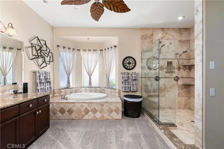 Primary Bathroom with Soaking Tub, Vanity Area, Walk In Shower and Ceiling Fan.