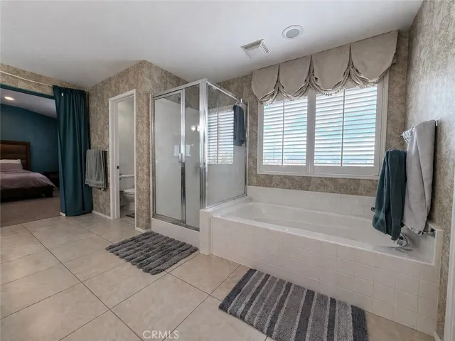 Primary ensuite bathroom jetted soaker tub, shower, entrance to toilet, and door to primary bedroom