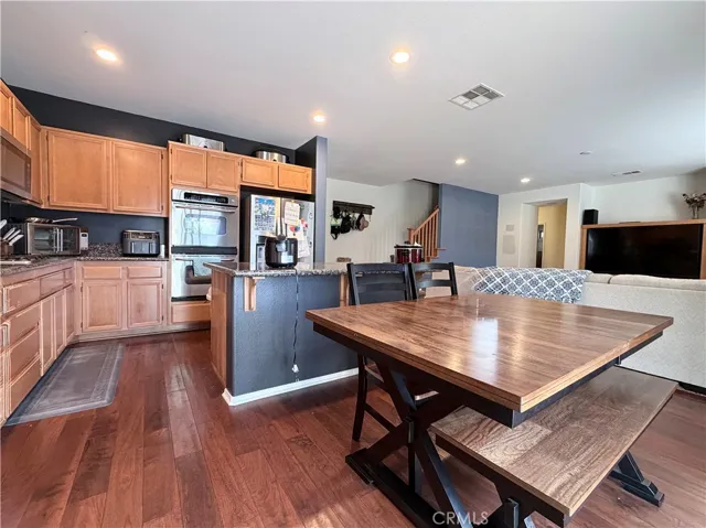 Wide angle view of kitchen with family room, stairs and door that leads to main floor bedroom and bathroom at the back