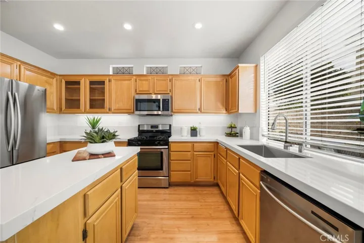 Sunlit Kitchen has High Transom Windows for Lots of Natural Light, LED Recessed Lighting, Quartz Countertops, Maple Cabinetry with Glass Display Panels