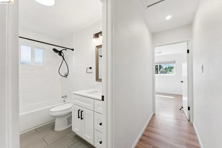 Bathroom with vanity, wood tiled floors, and washtub / shower combination