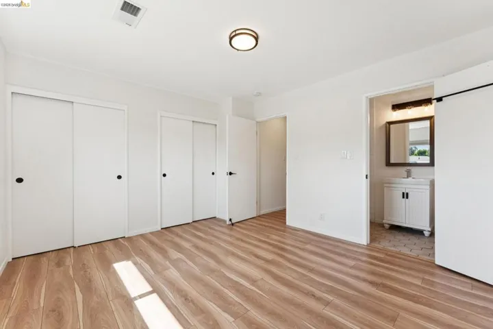 Unfurnished bedroom featuring multiple closets, light wood-style flooring, and connected bathroom