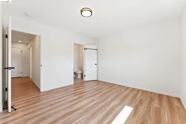 Unfurnished bedroom featuring light wood finished floors and ensuite bathroom