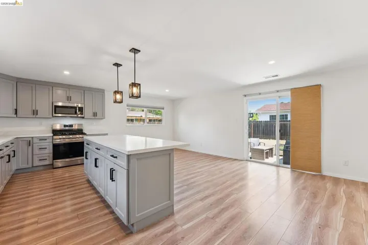 Kitchen with gray cabinetry, stainless steel appliances, open floor plan, and a center island