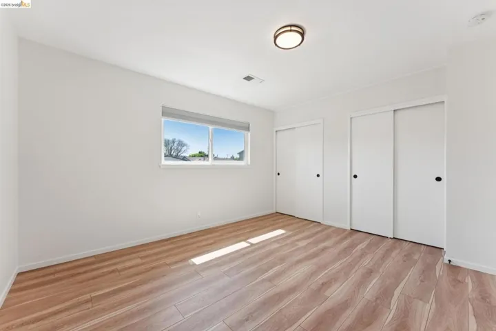 Unfurnished bedroom featuring two closets and light wood-style floors