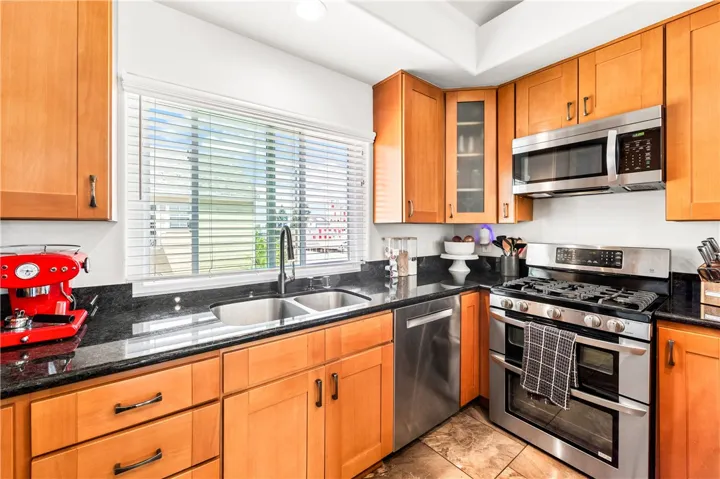 Kitchen-complete with granite counter tops, wood cabinetry, and stainless appliances.
