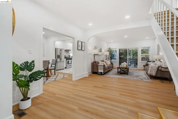 Bright open-concept living area featuring light wood-finish flooring, recessed lighting, and a white baluster staircase
