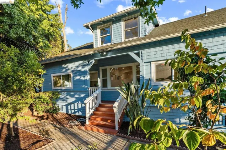 Blue siding exterior with dormer windows, featuring a covered porch entry and white baluster railing