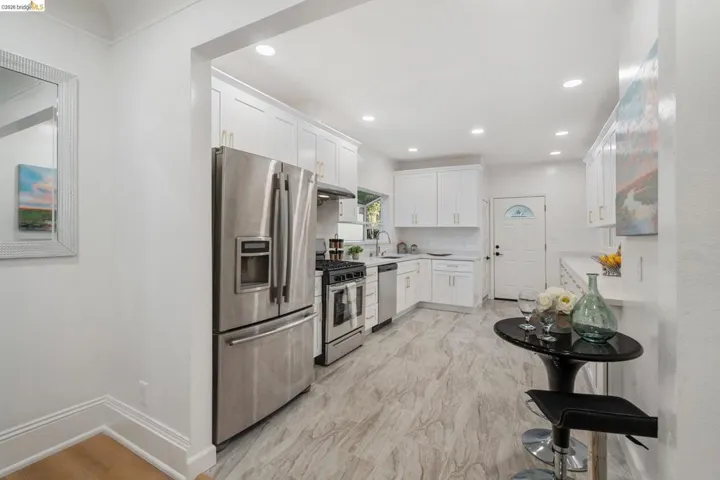 Modern kitchen featuring white shaker cabinetry, stainless steel appliances, light-toned wood-finish flooring, and recessed lighting