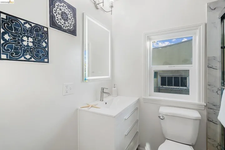 Contemporary bathroom featuring a white vanity with integrated sink, chrome faucet, and an illuminated mirror