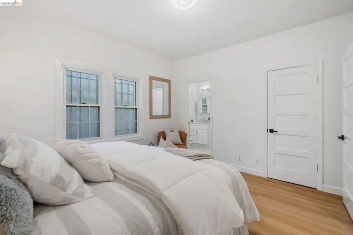 Bedroom featuring light wood-finish flooring, white walls, and a contemporary ceiling light fixture