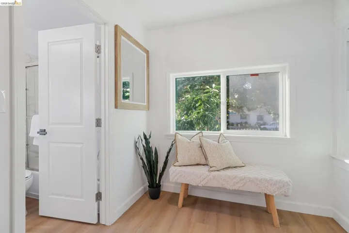 Bright interior space featuring a window with exterior views, light wood-finish flooring, and white baseboards