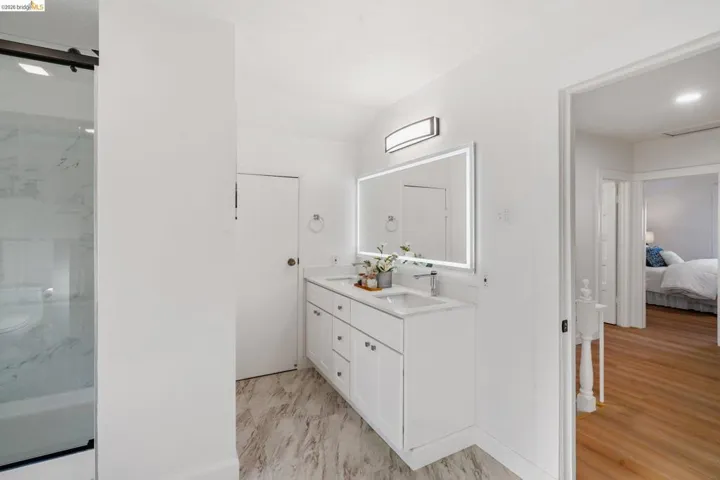 Contemporary bathroom featuring a double vanity with integrated sinks and a large backlit mirror
