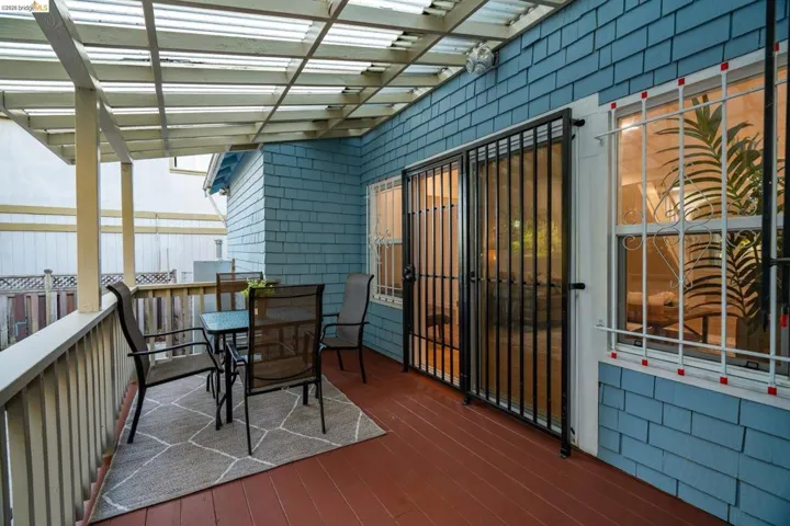 Covered outdoor patio area featuring a slatted wood pergola, painted wood deck, and blue shake siding
