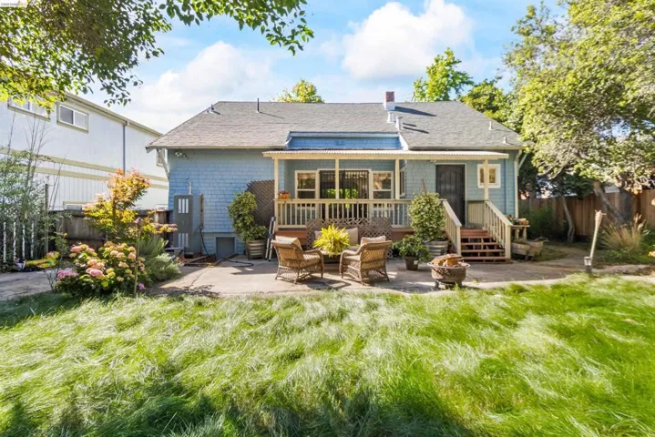 Rear exterior featuring a concrete patio, wood deck, and expansive lawn