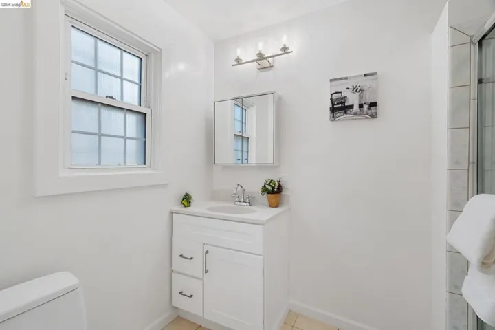 Bathroom featuring a white vanity with integrated sink, chrome faucet, and mirrored medicine cabinet