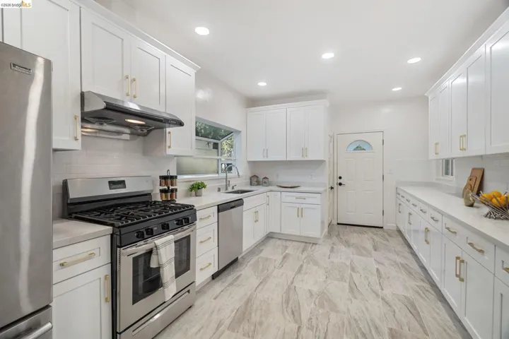Contemporary kitchen featuring white cabinetry, stainless steel appliances, light-toned countertops, a subway tile backsplash, and wood-finish flooring