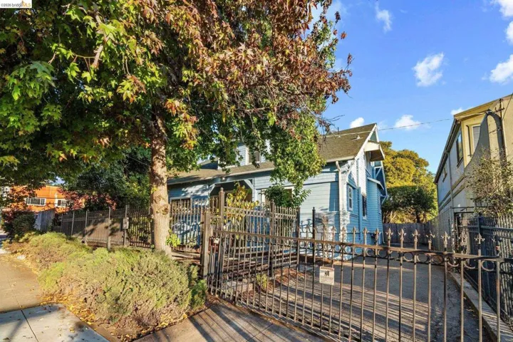 Gated property entrance featuring wrought iron fencing and a paved drive