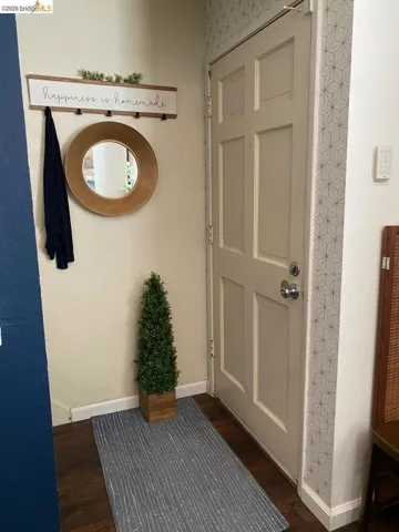 Panel door entry featuring wood-finish flooring, geometric-patterned accent wall, and a contrasting dark wall