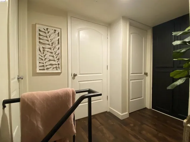 Warm wood-finish flooring complements a hallway featuring white paneled doors, light-toned walls, and a dark built-in storage unit