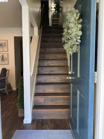 Staircase featuring wood-finish treads and risers, white painted balusters, and a dark handrail