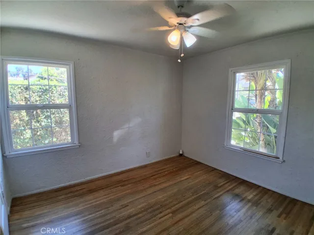 The first bedroom offers a bright, open feel with a ceiling fan and abundant natural light.