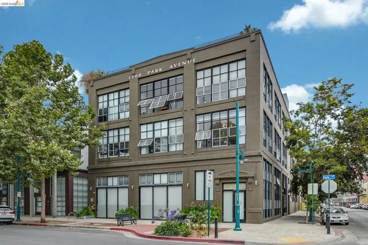 Multi-story building featuring industrial-style architecture, prominent grid windows, a flat roofline, and ground-level street access