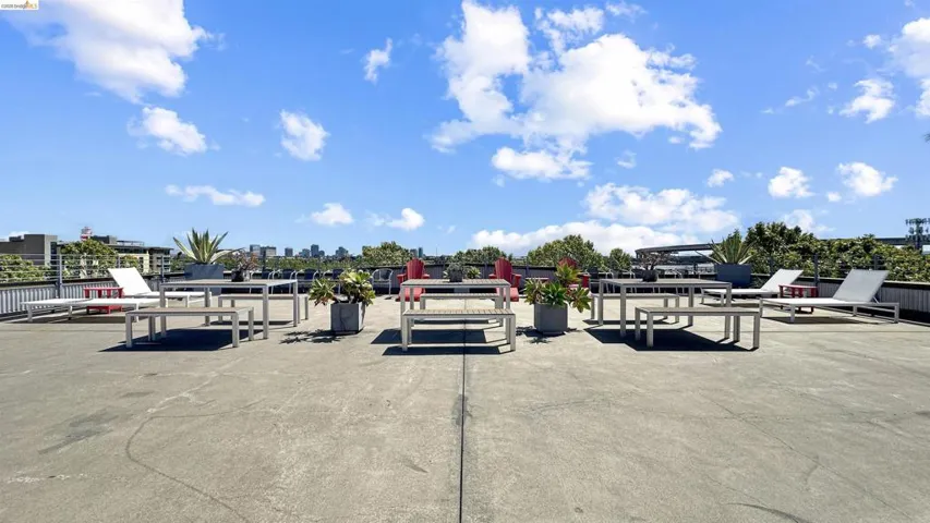 Expansive rooftop deck featuring a flat surface, perimeter railing, and distant cityscape