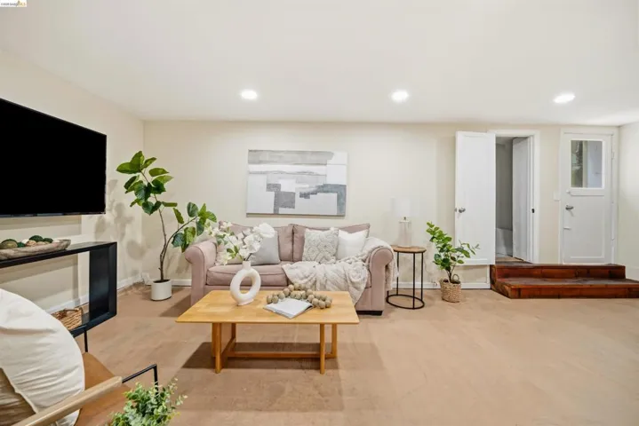 Spacious living area featuring light-toned flooring, recessed lighting, and neutral wall tones