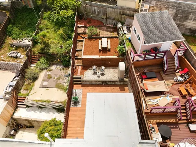 Multi-level rear outdoor space featuring wood decking, a built-in shed with a shingled roof, and terraced areas