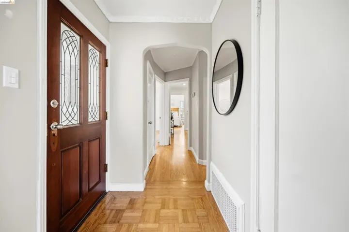 Entryway featuring a wood-finish door with leaded glass panels, parquet wood-finish flooring, and crisp white trim