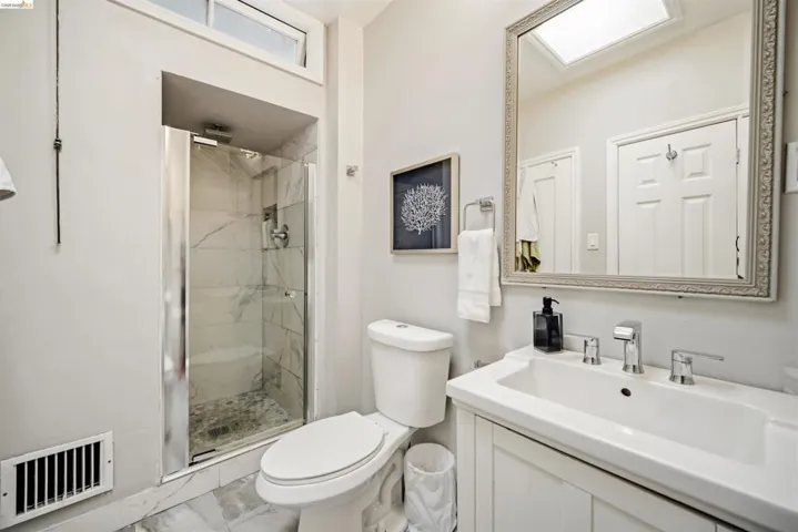 Modern bathroom featuring a glass-enclosed shower with tile surround, white vanity with integrated sink, and an ornate framed mirror