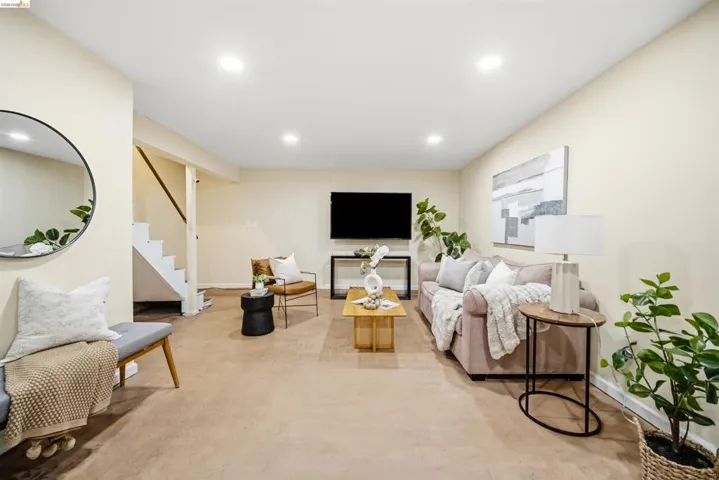 Open-concept living area with light-colored walls, recessed lighting, and wood-finish flooring