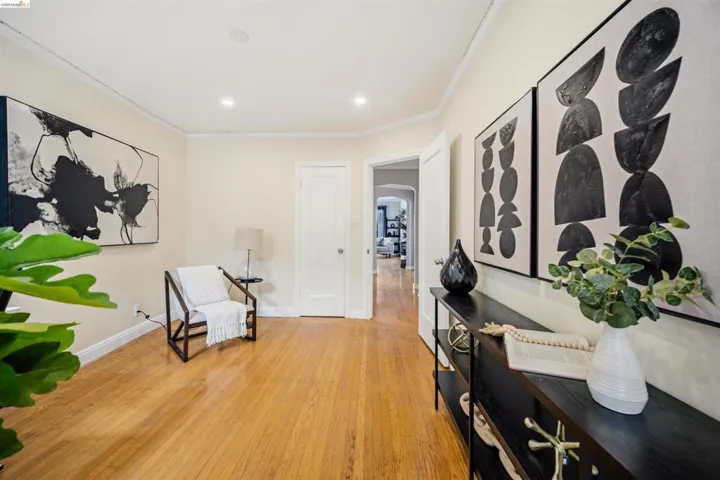 Hardwood flooring throughout entryway with white baseboards and crown molding