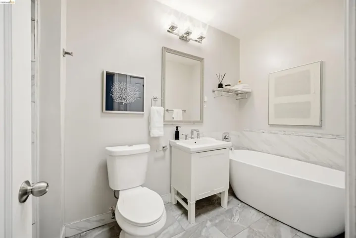 Modern bathroom featuring a freestanding soaking tub, single vanity with integrated sink, and a wall-mounted light fixture